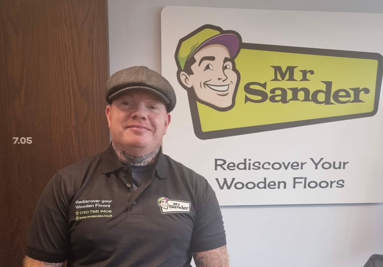 Man wearing hat and shirt stands in front of 