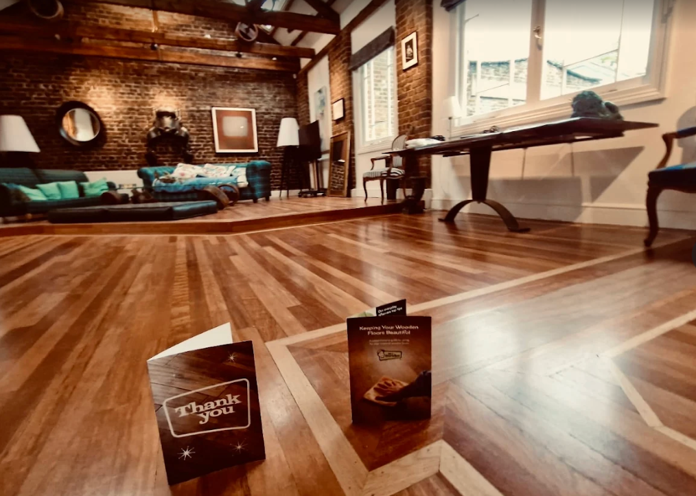 Hardwood floor with two brochures in foreground, couches, and art in a room.