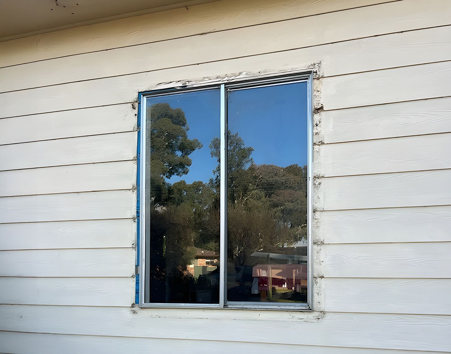 A Newly Installed Window In A White Siding Wall