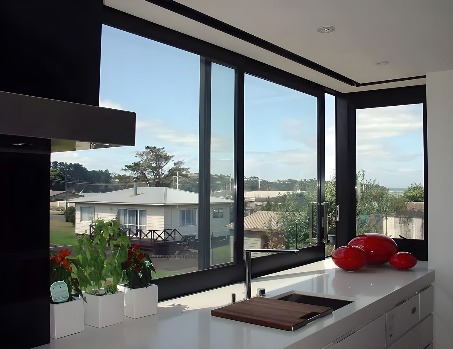 Modern Kitchen With Sliding Windows Overlooking A Residential Neighborhood