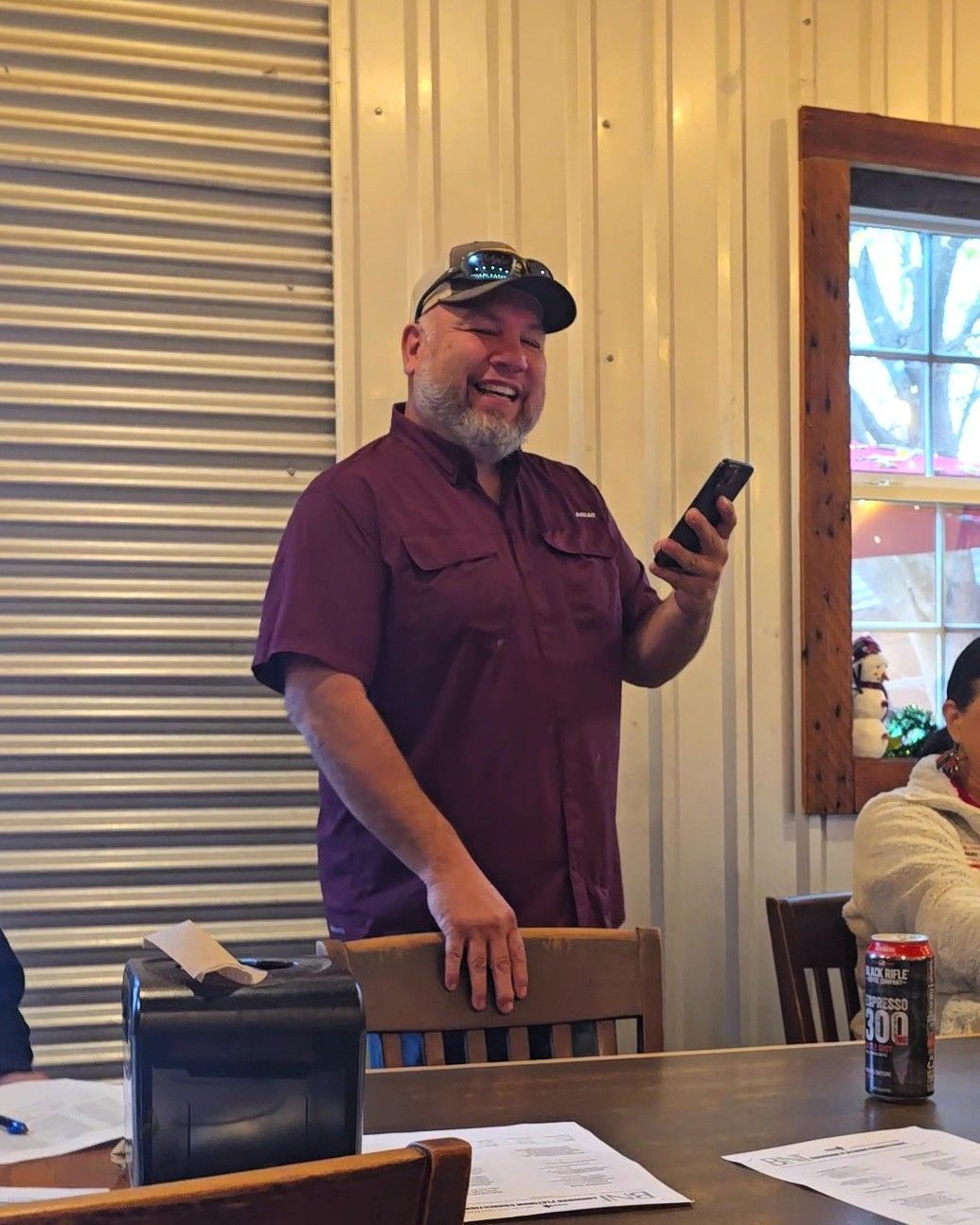 Man in striped shirt fixing a kitchen faucet, leaning over a stainless steel sink.