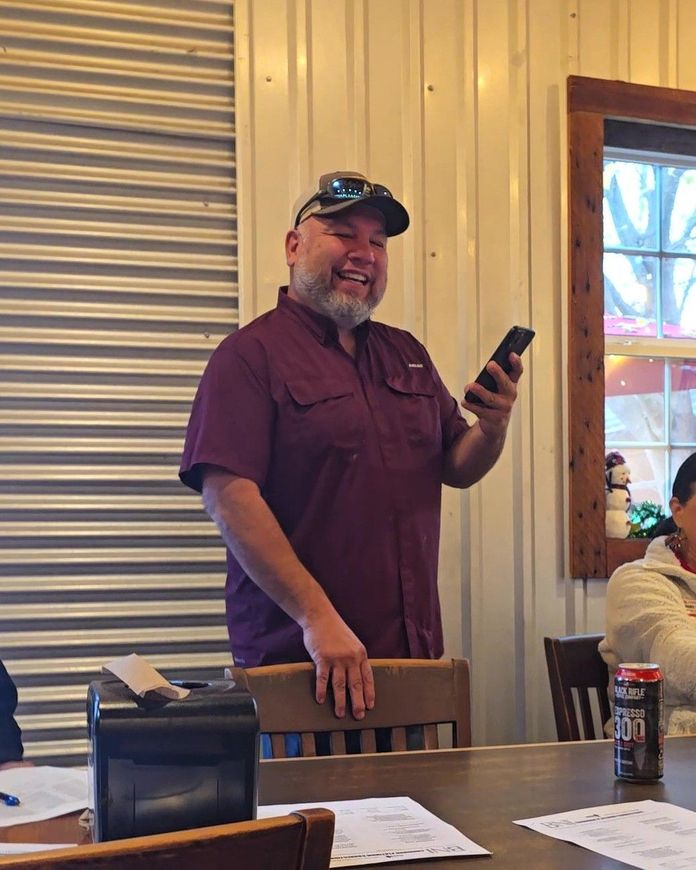 Man in striped shirt fixing a kitchen faucet, leaning over a stainless steel sink.