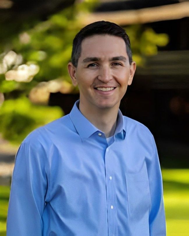 A man in a blue shirt is smiling for the camera.