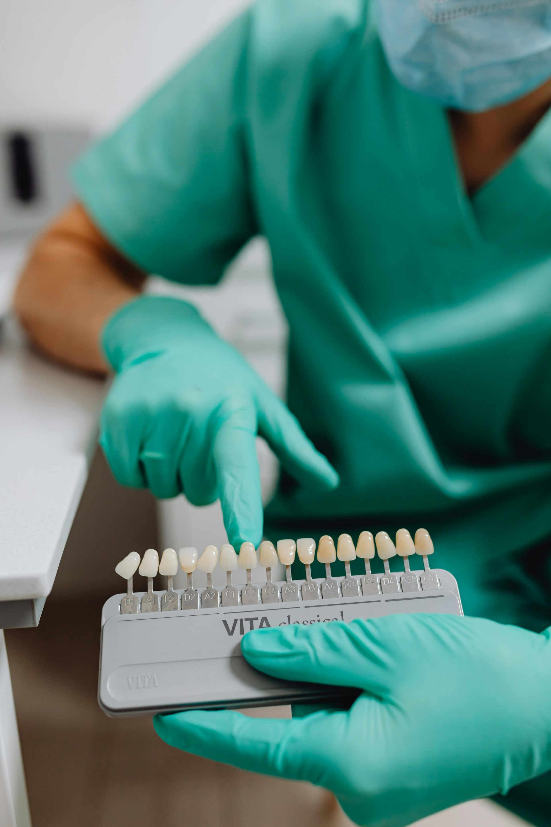 A dentist is holding a tray of teeth and pointing at them.