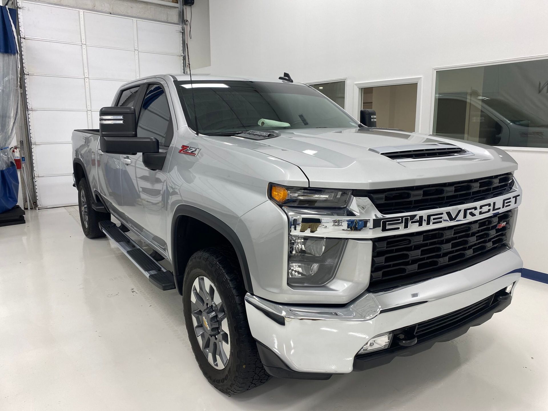 A silver chevrolet truck is parked in a garage.