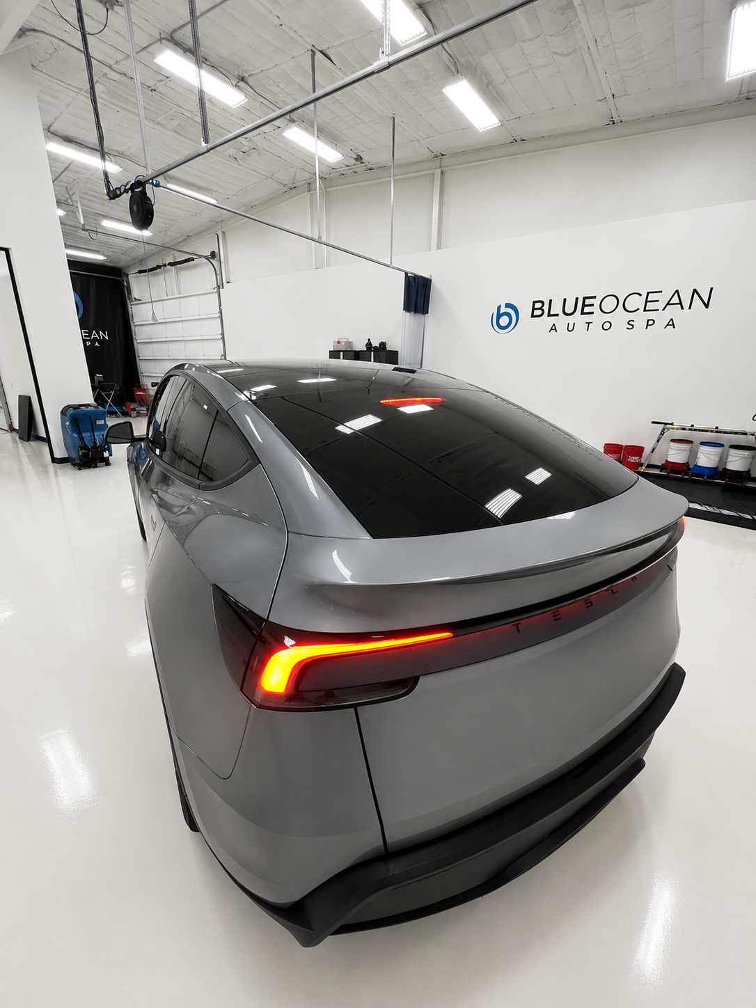 A 2026 Tesla Model Y now tinted with a dark tint on the windows.  It is parked in an exceptionally clean shop.