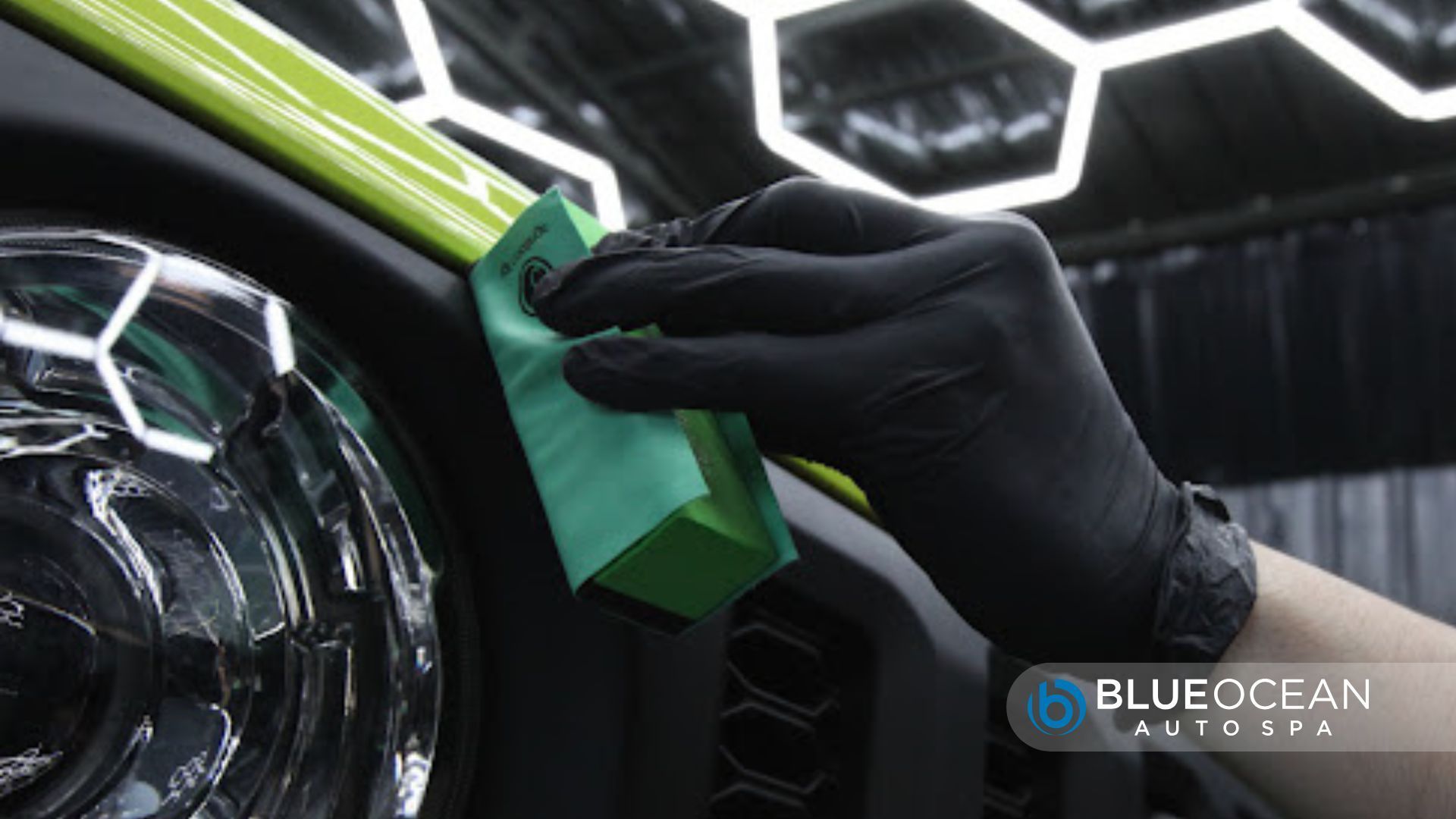 A gloved hand applies ceramic coating to a lime green car trim near the headlight