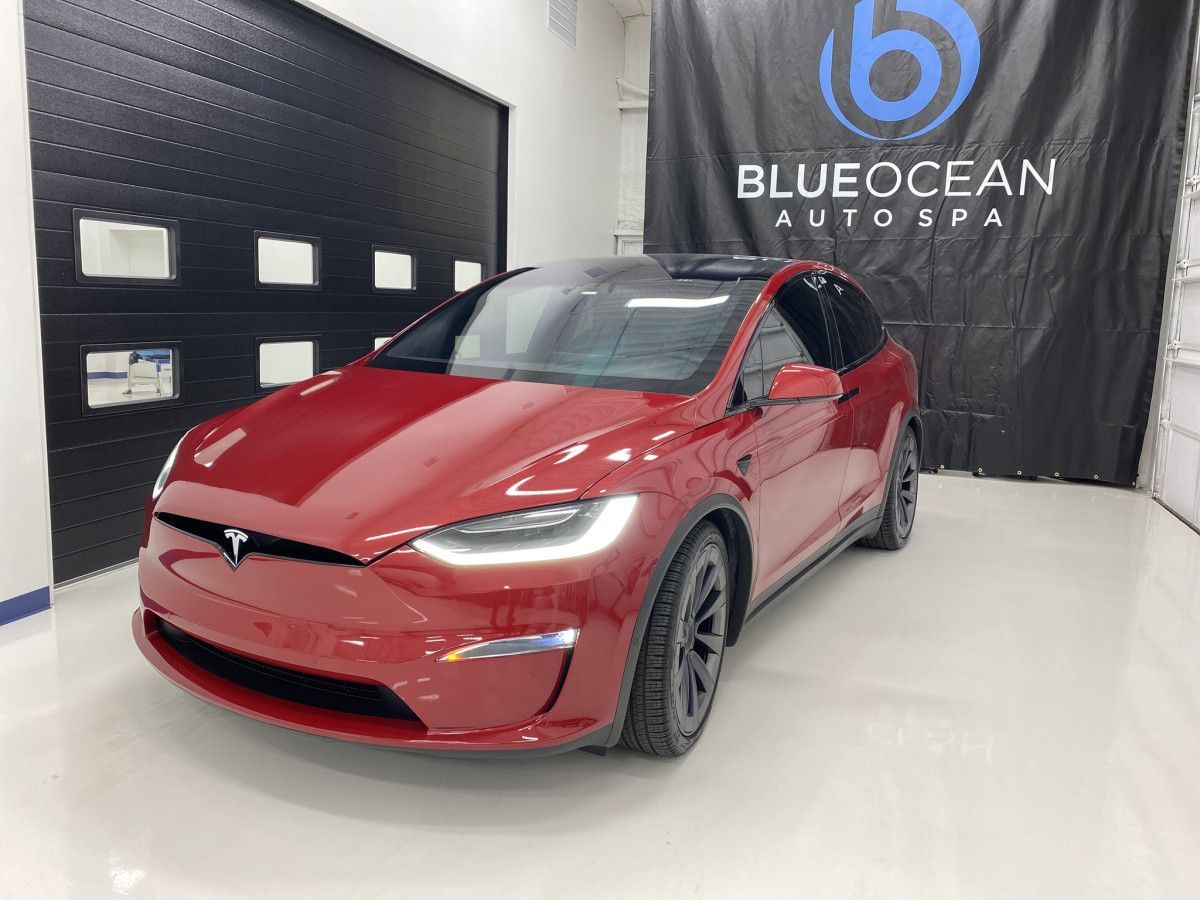 A red tesla model x is parked in a garage.