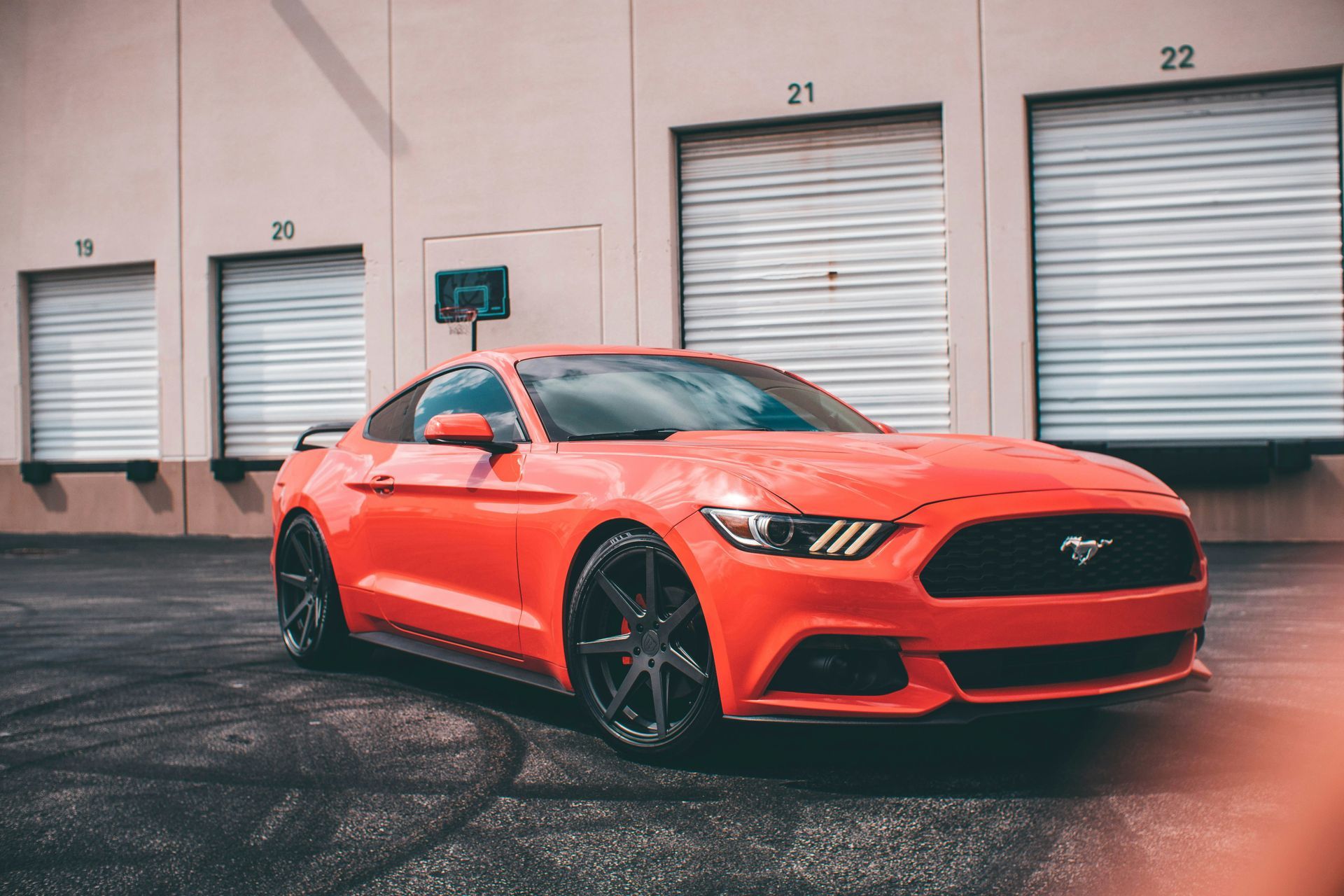 A red ford mustang is parked in front of a building.
