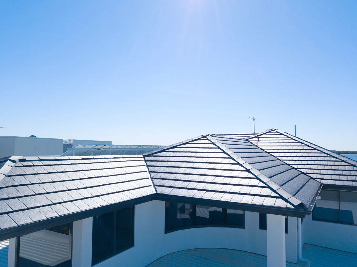 An aerial view of a house with a tiled roof and a blue sky in the background.