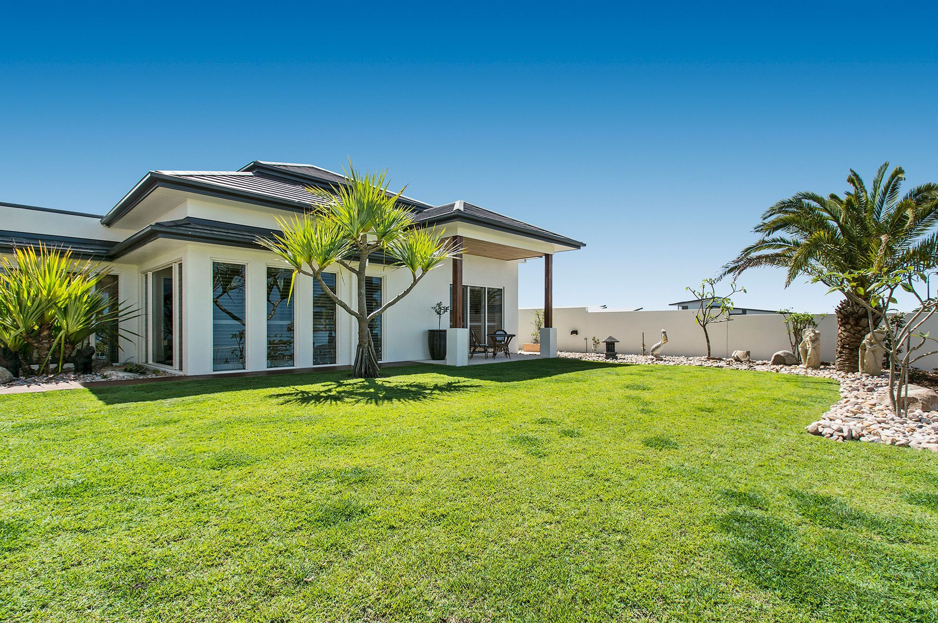 A Large White House With a Lush Green Lawn in Front of It — Mr Roof Tiles in Byron Bay, NSW