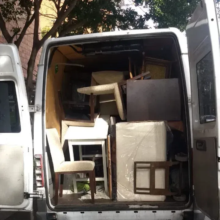 Interior de camioneta lleno de muebles, incluidas sillas, mesas y un artículo en caja.