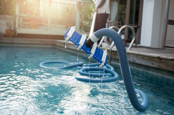 Pool vacuum cleaner attached to hose cleaning water in an indoor swimming pool