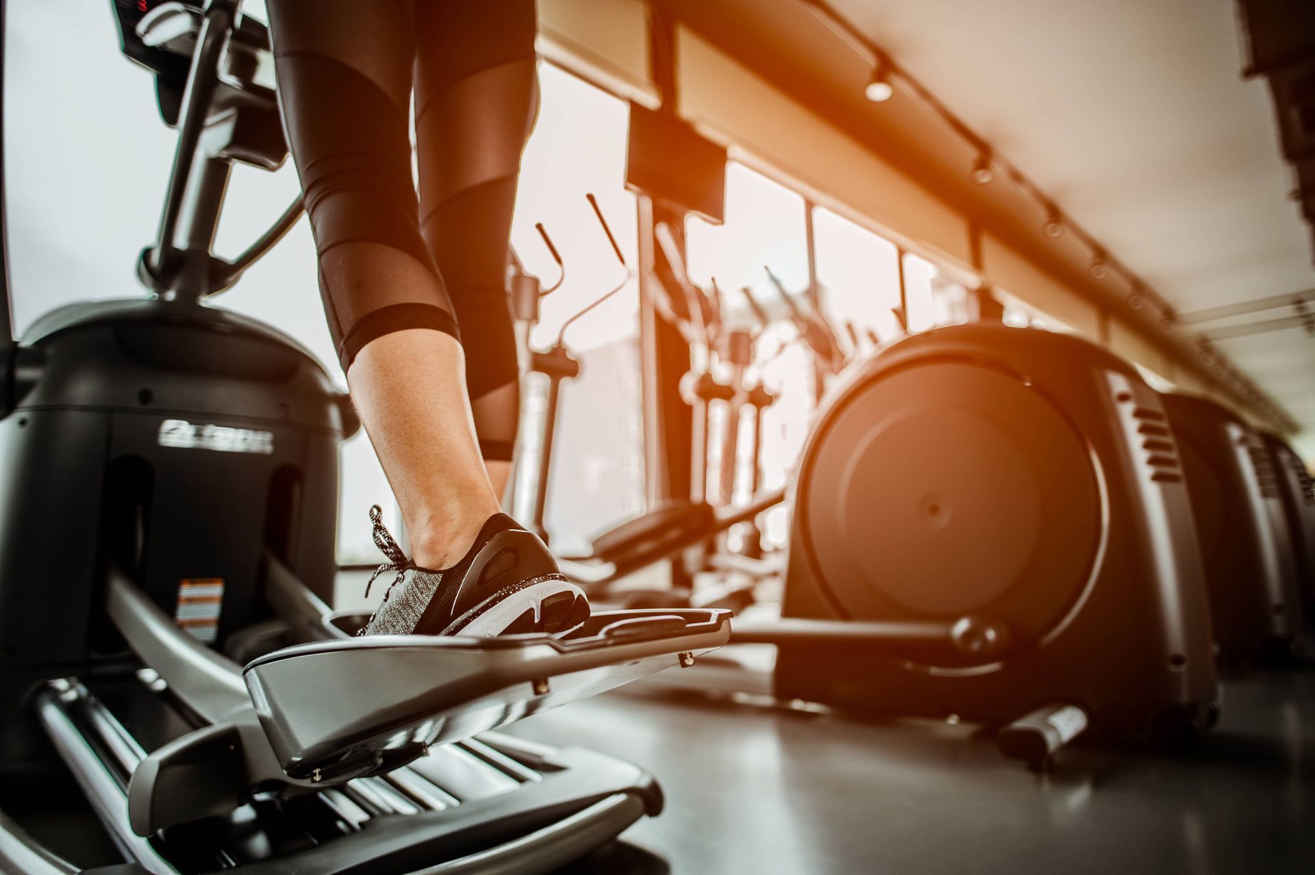 A woman is riding an elliptical machine in a gym.