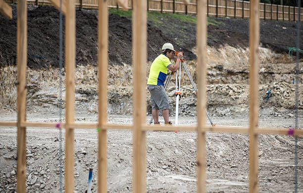 A Construction Worker Is Working On A Construction Site Behind A Wooden Fence – Warrnambool, VIC - Joseph Land Surveying