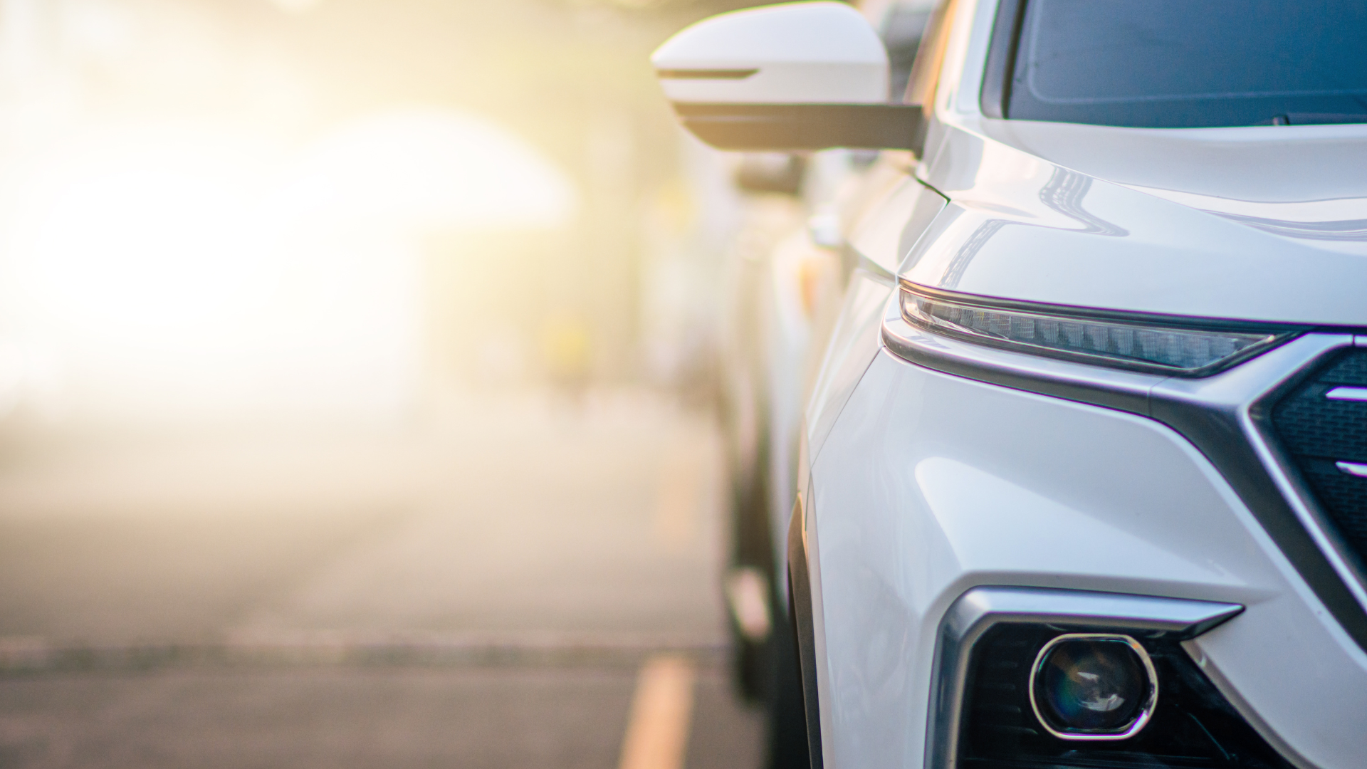 A close up of a white car parked on the side of the road.