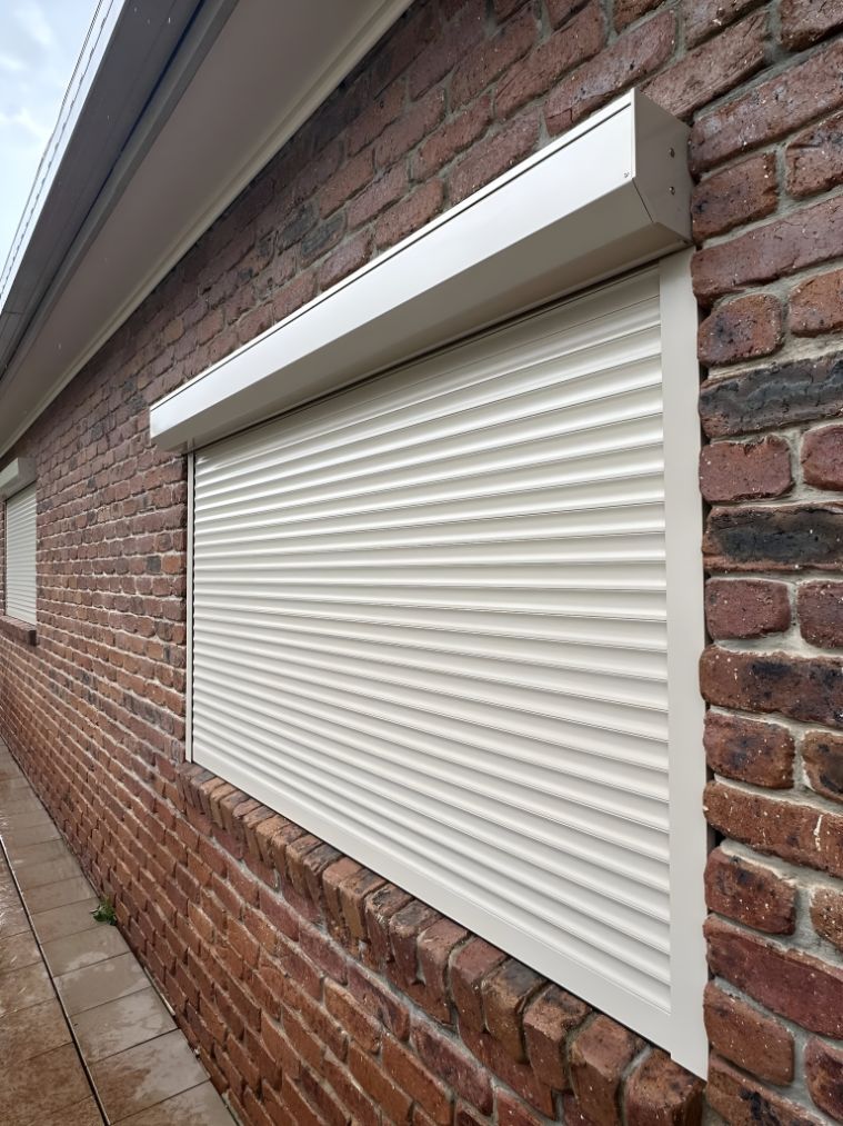 A Brick Building With a White Roller Shutter on the Window β South Burnett Garage Doors In Kingaroy, QLD