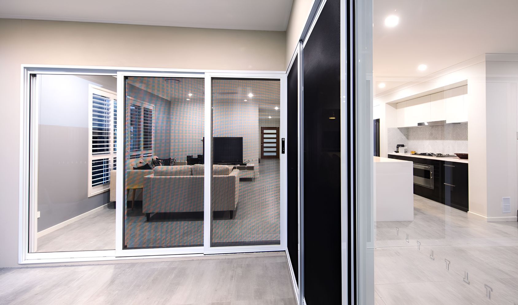 A Living Room and Kitchen Are Visible Through a Sliding Glass Door β South Burnett Garage Doors In Kingaroy, QLD
