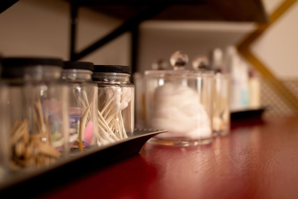 A shelf filled with jars of cotton swabs and cotton balls.