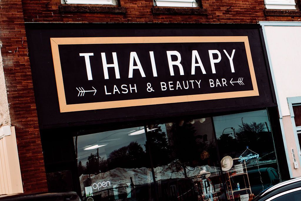 A thairapy lash and beauty bar is located on a brick building.