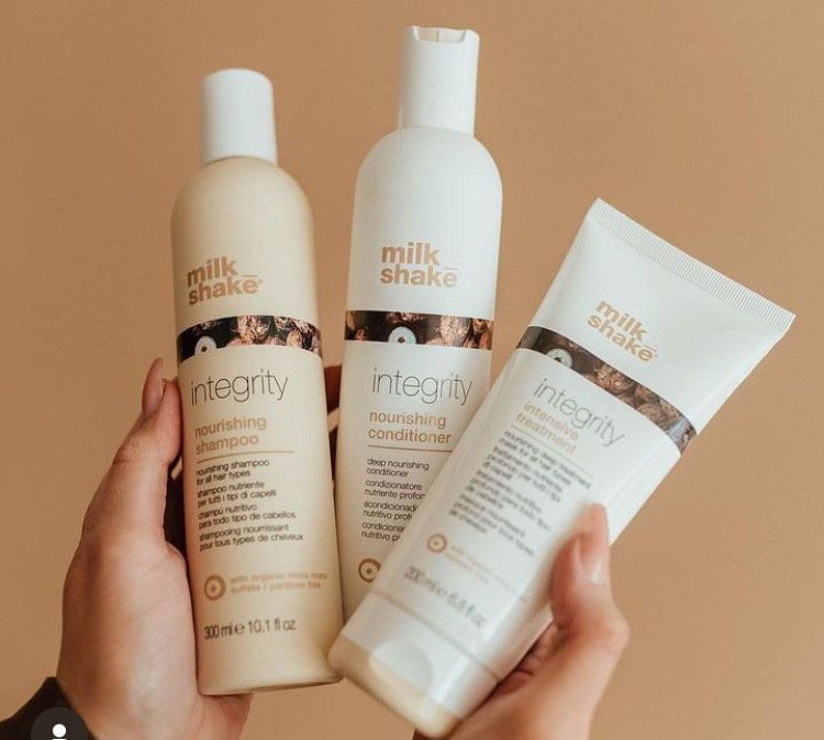 A person is holding three bottles of milk shake integrity