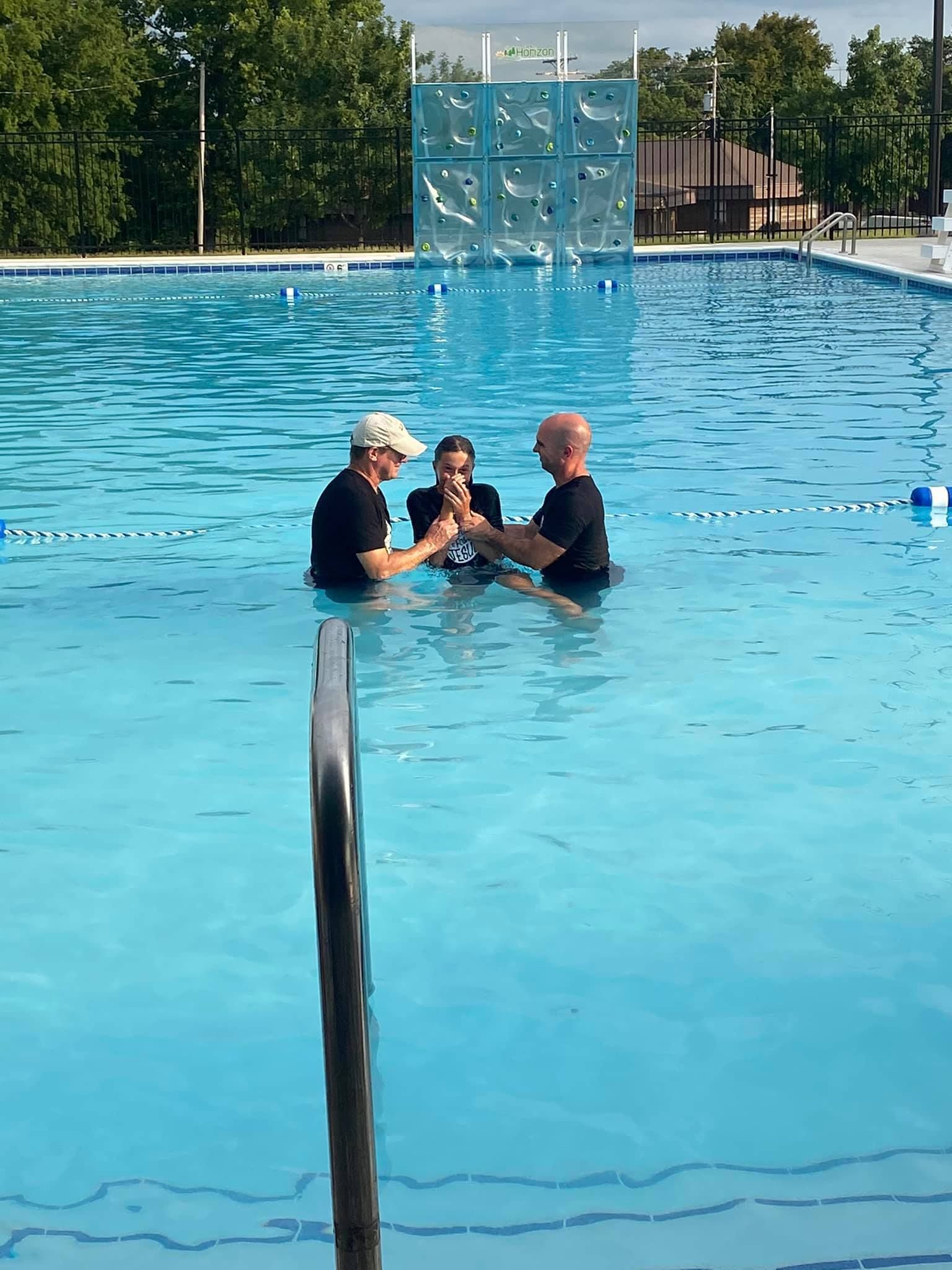A man is being baptised in a swimming pool.