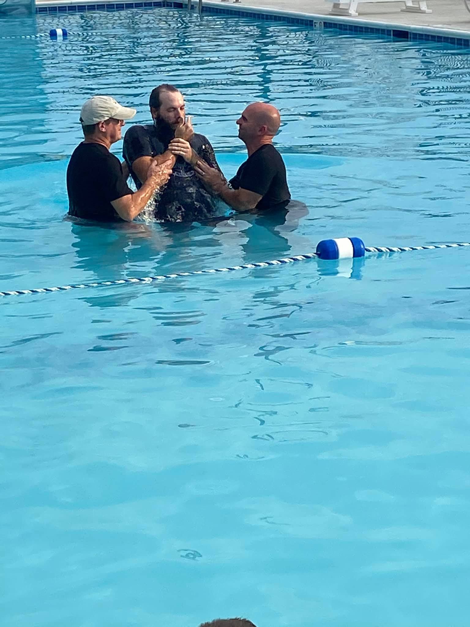 A man is being baptised in a swimming pool.