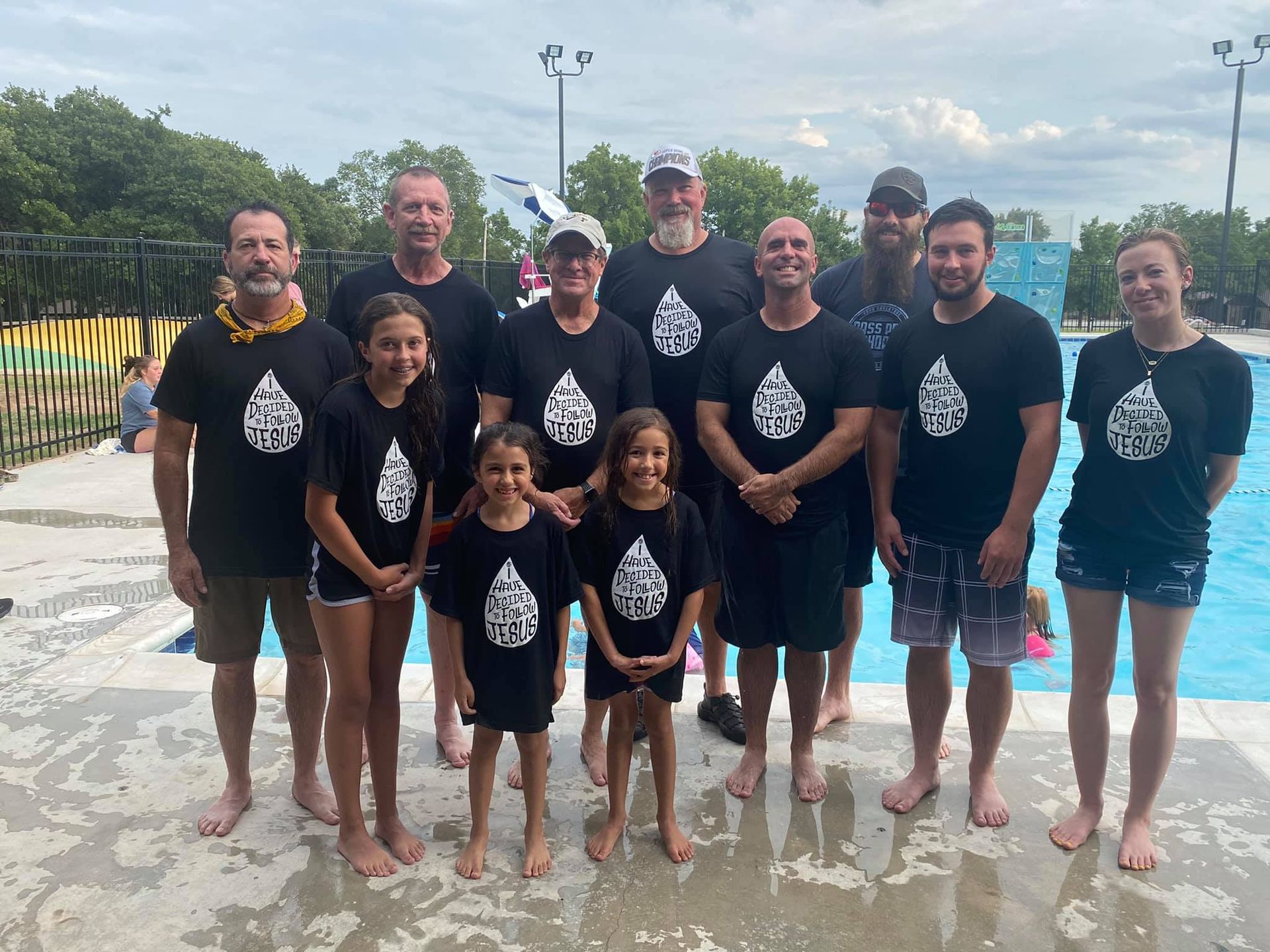 A group of people are posing for a picture in front of a swimming pool.