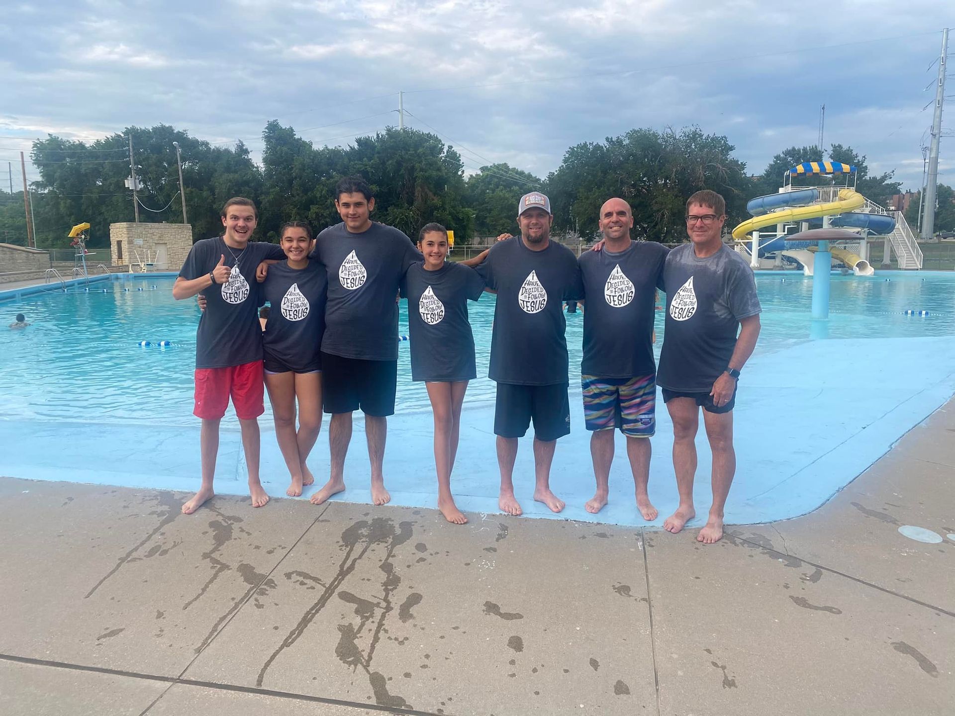 A group of people are posing for a picture in front of a swimming pool.