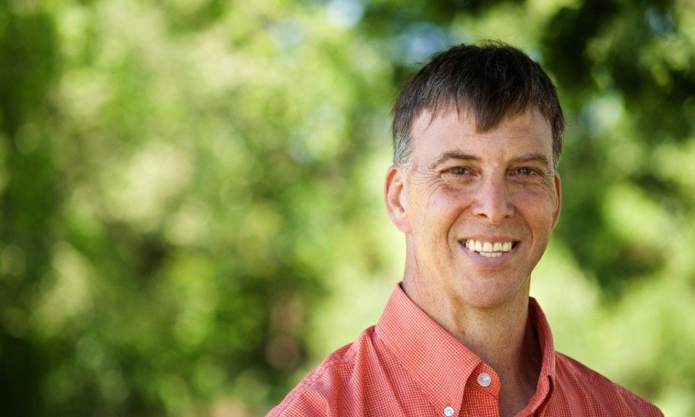 A man in an orange shirt is smiling for the camera.