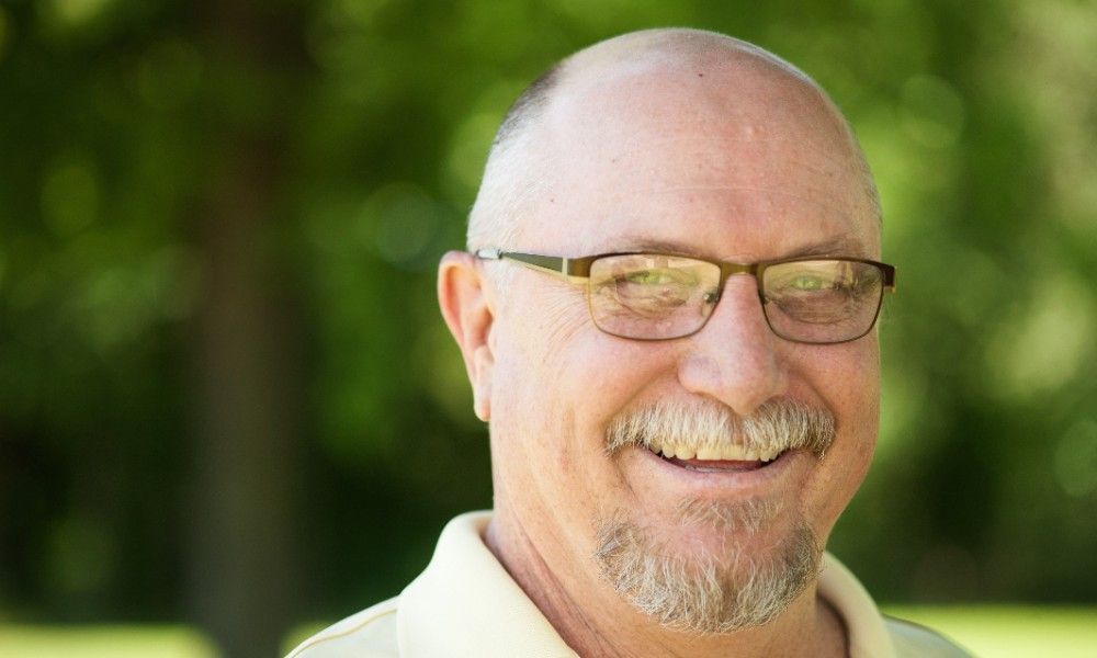 A man with glasses and a beard is smiling for the camera.