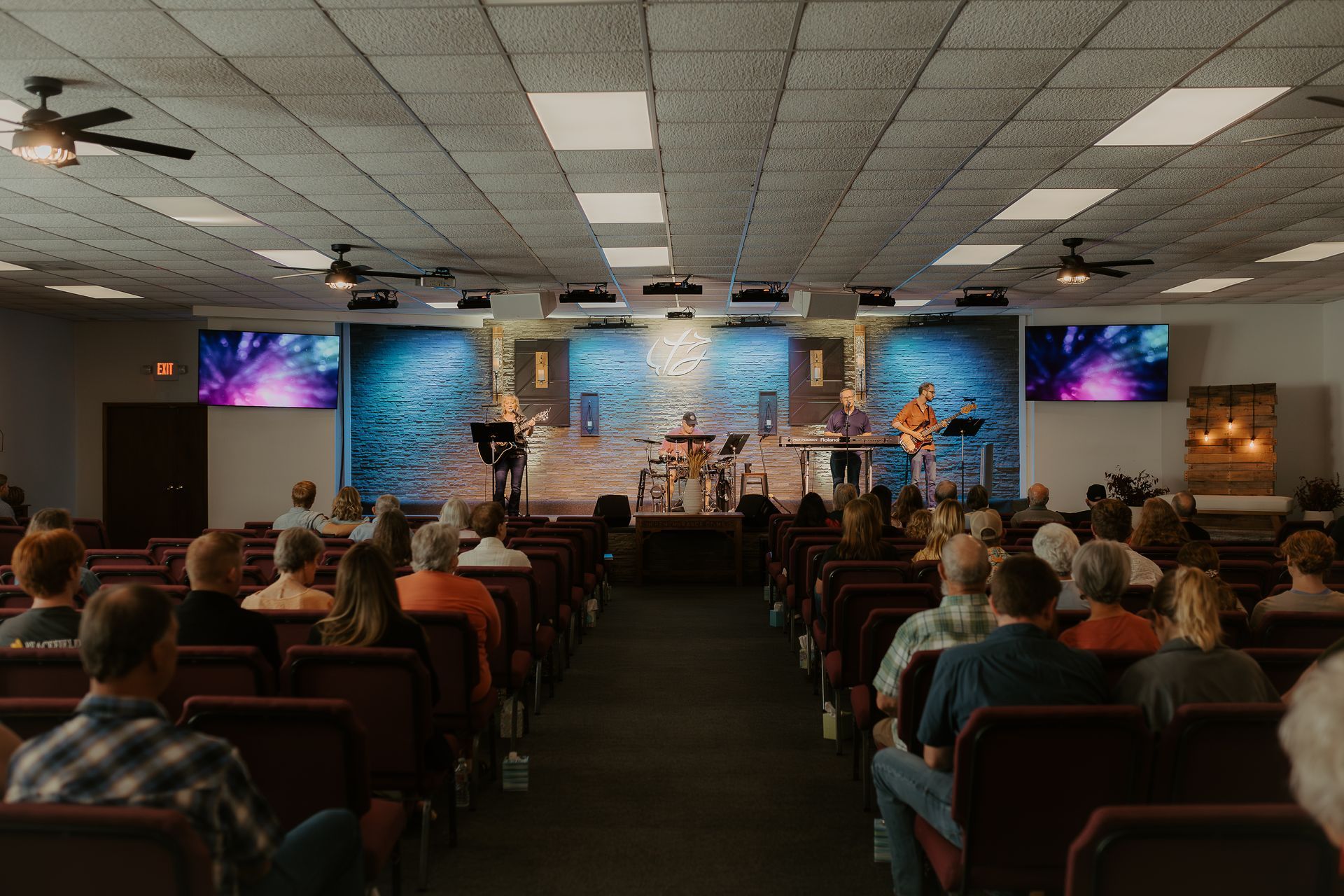 A large group of people are sitting in a church watching the band.