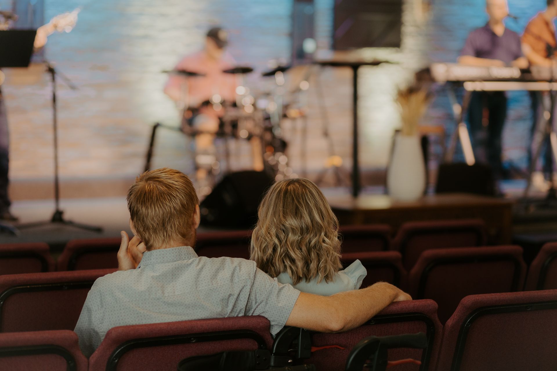 A man and a woman are sitting in a church watching the band.