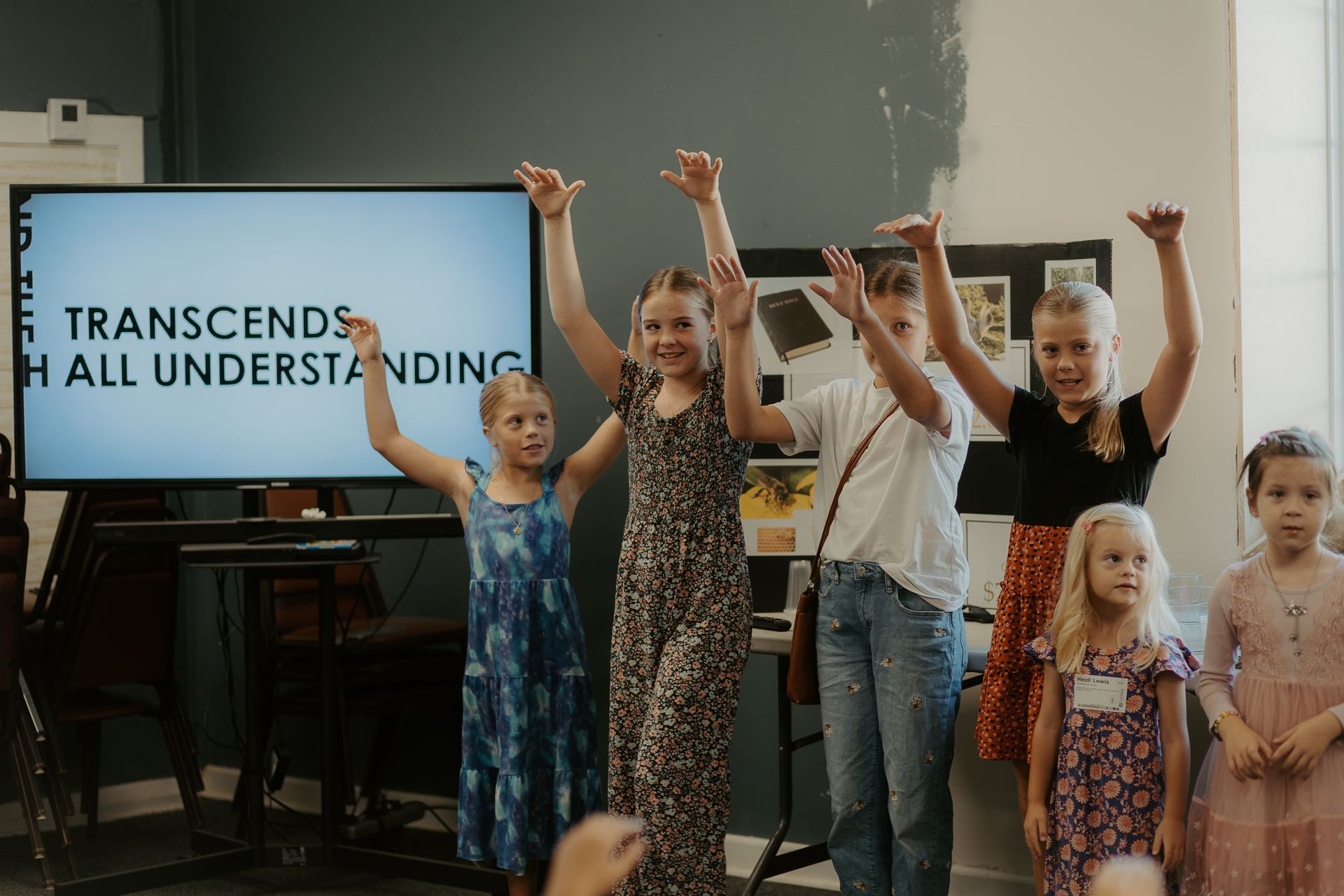 A group of young girls are standing in front of a large screen with their hands in the air.