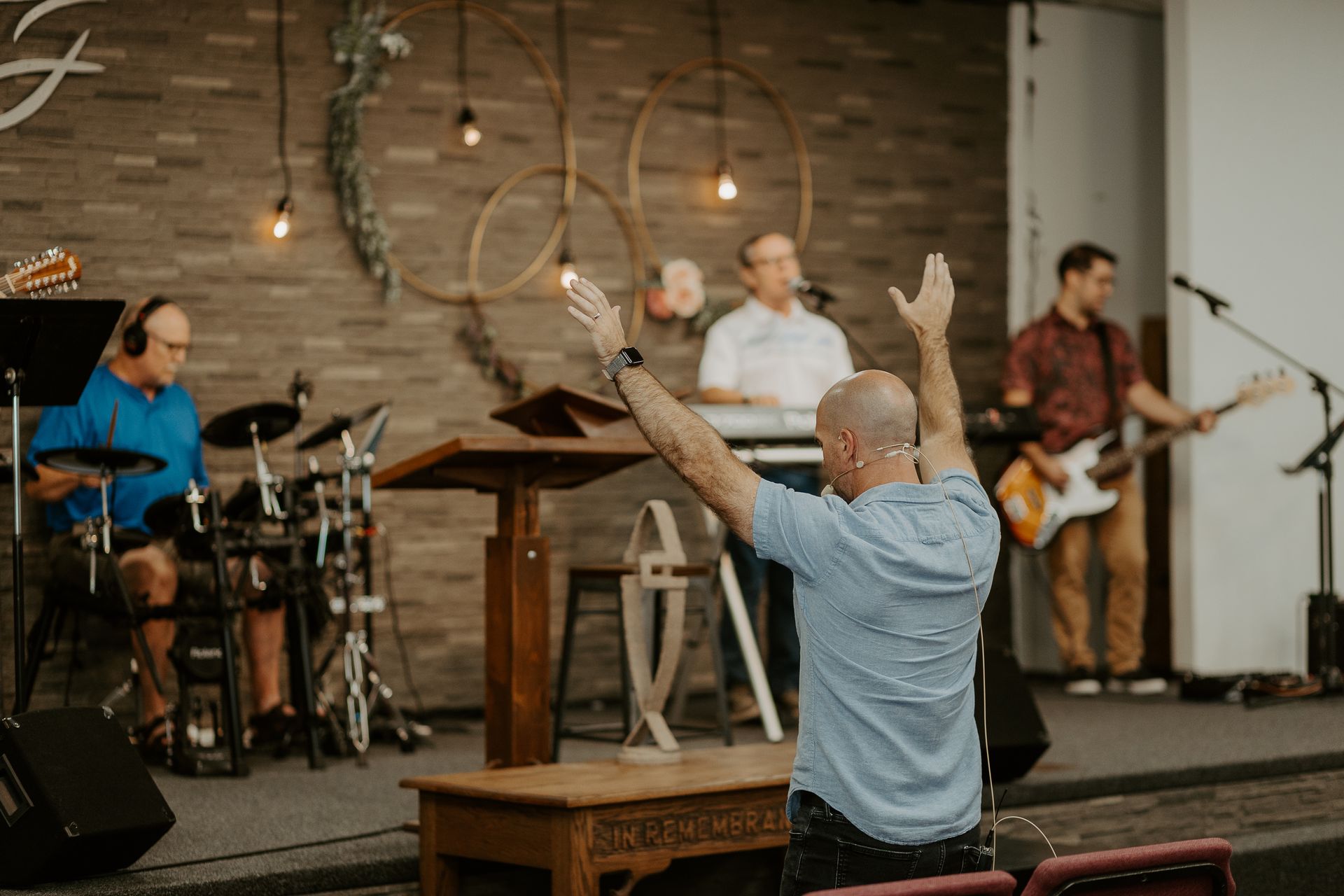 A man is kneeling at a podium with his hands in the air in front of a band.