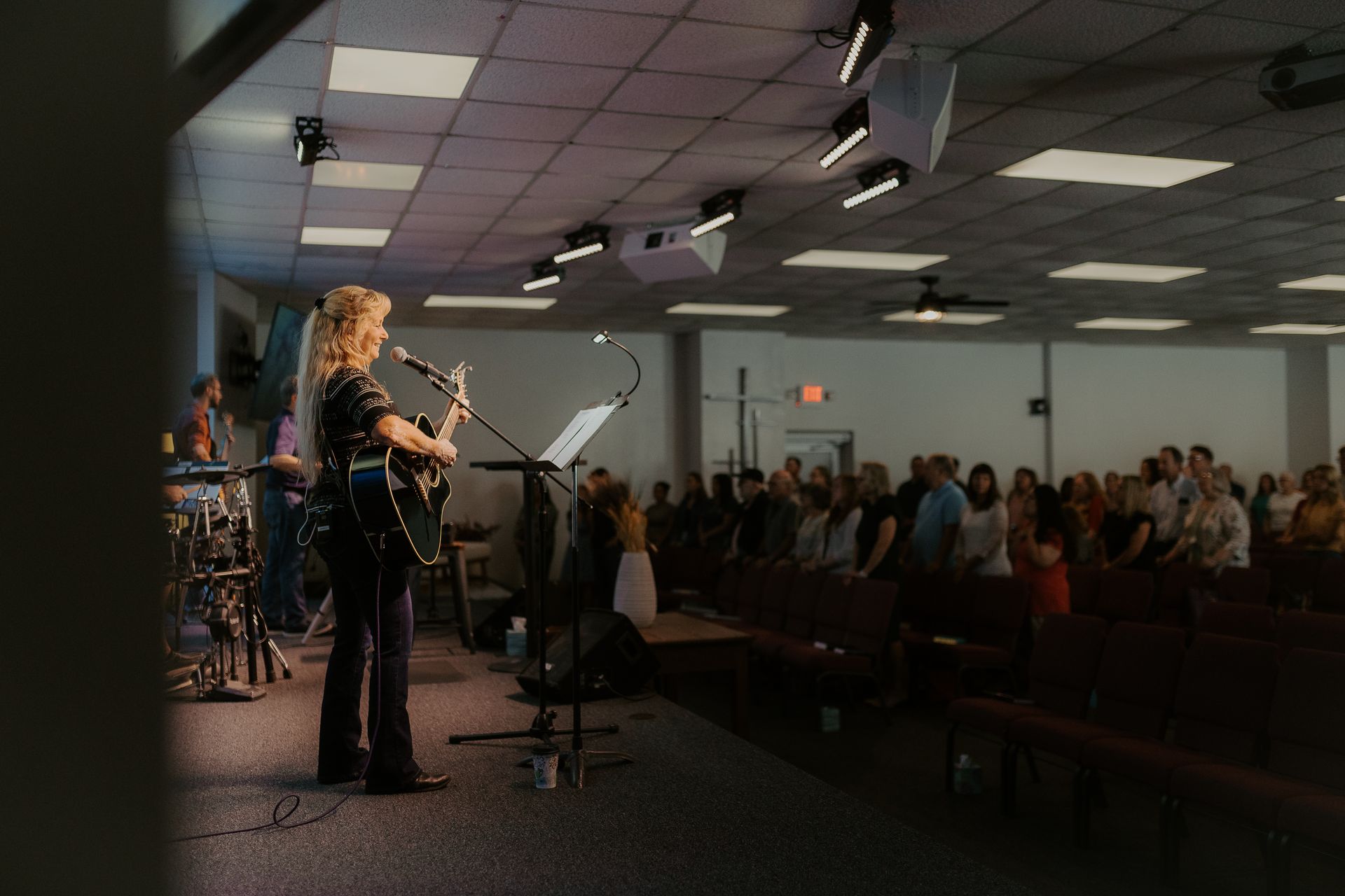 A woman is singing into a microphone in front of a crowd in a church.