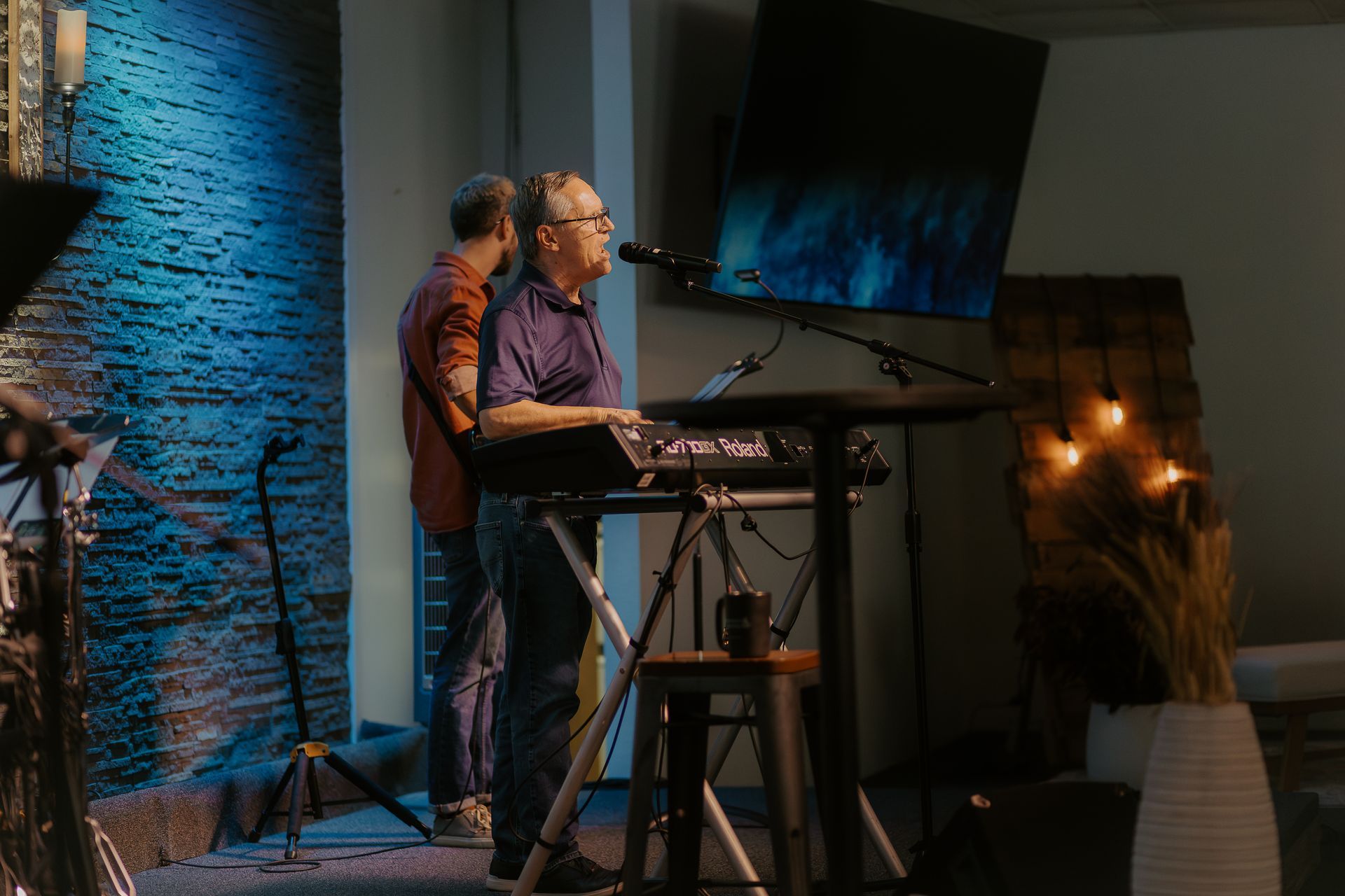 A man is playing a keyboard and singing into a microphone on a stage.