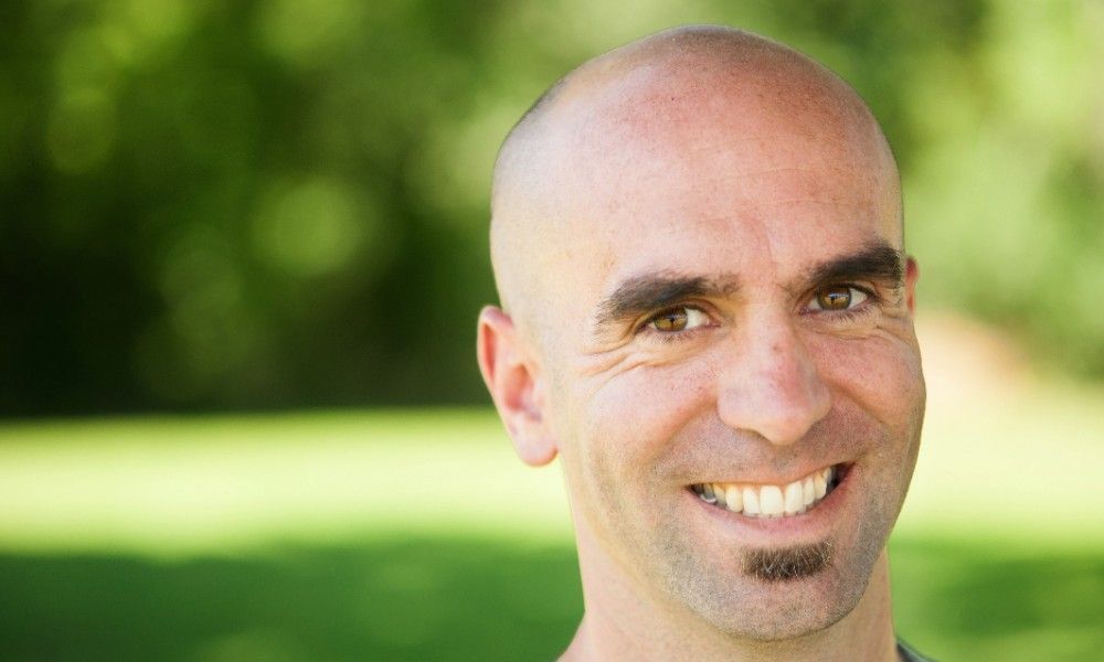 A close up of a man smiling in a park.