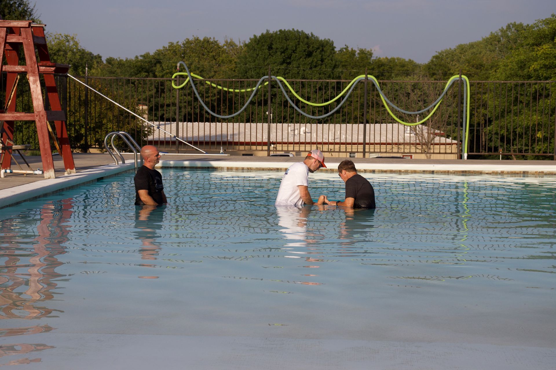 A little girl is being baptized in a swimming pool