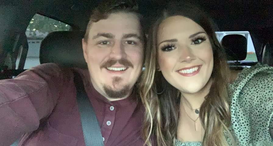 A man and a woman are taking a selfie in a car.