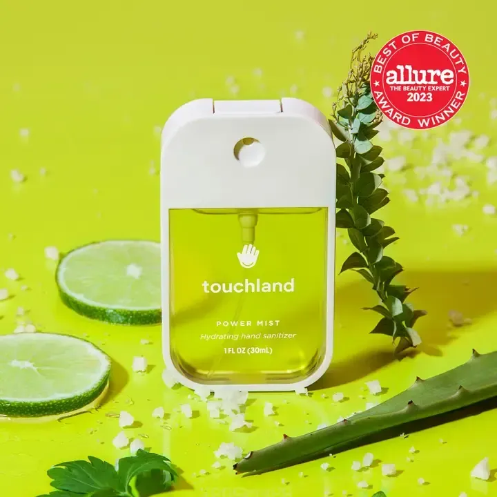 A bottle of touchland hand sanitizer is sitting on a yellow table.