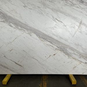 White marble slab with gray and gold veining, resting on a yellow support.