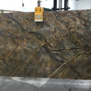 Large slab of brown and gold patterned stone being moved by a lifting device.