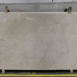 Large beige stone slab, with subtle veining, on a wooden rack.