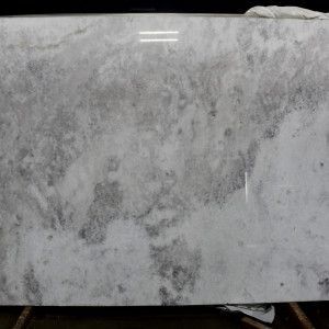 A large slab of white marble with gray veining and a polished surface, displayed indoors.
