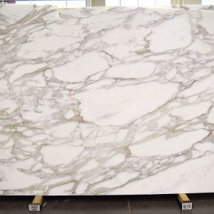 White marble slab with gray veining, displayed on a wooden stand.