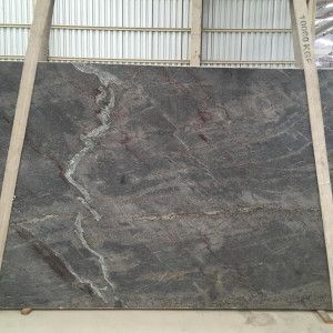Large gray granite slab with flowing white and reddish veining, indoors.