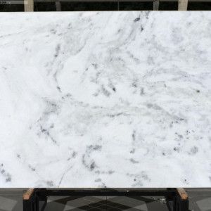 White marble slab with gray veining and dark speckles.