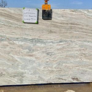 A large slab of light-colored marble, with brown and gray veining, under a bright sky.