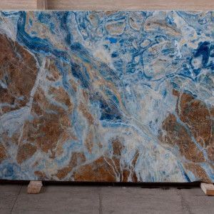 Large slab of stone with brown, blue, and white swirling patterns, likely for countertops.